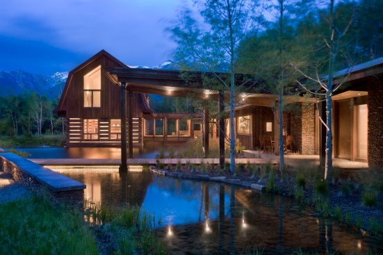Exterior, horizontal, view from east of barn (left) connecting to main house (right) with pond in the foreground at twilight, Kahlbetzer residence, Wilson, Wyoming; Ward + Blake Architects