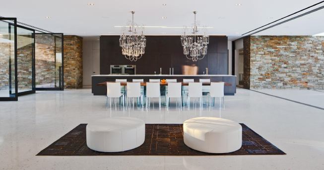 The kitchen occupies one end of a living space so open to the outdoors that it is defined mainly by the ceiling above.