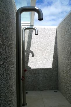 The master bathroom features pebble tiles and Italian-made pipe showers. A retractable skylight allows the owners to bathe alfresco.