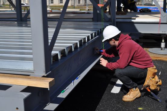 A student signs the steel frame of Team Capitol DC's Harvest House.