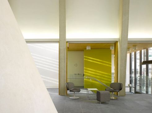 View from the caf?? to the entrance. The linear fluorescent direct/indirect lighting system is integrated into the architecture between the structural concrete columns. The fixtures create a datum at the architectural openings between the central sanctuary spaces and the entrance, community rooms, and cafe.