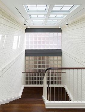 The stair was relocated from the front hall to the space between the existing house and addition. Lay lights, a wall of glass block, and Velux skylights (veluxusa.com) allow light to enter the stairwell.