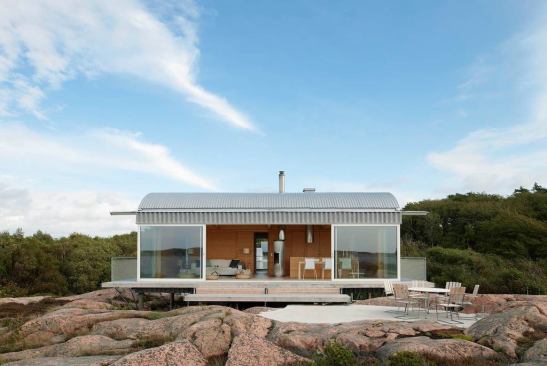 A 16-foot sliding glass door opens the main living space to a wood deck that spills onto the exposed bedrock of the shore.