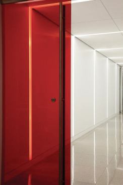 A red glass door marks the entry to the main-level dining area and the "lines of light" motif continues beyond to create a series of light frames.