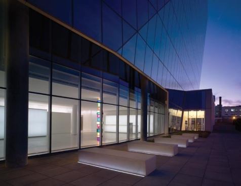 A view of the lobby from the exterior courtyard. Concrete benches are grazed with in-grade linear LED uplights. Beyond the lobby is a fitness center that will eventually link to Phase II of the building.