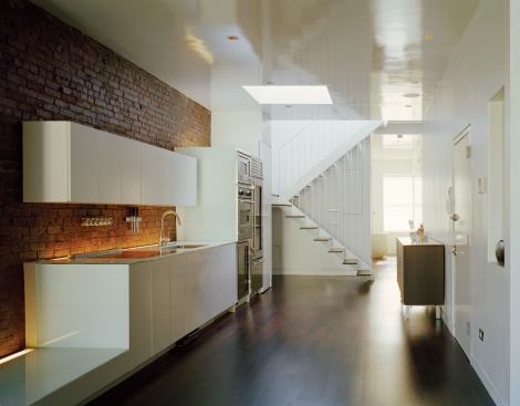 Light washes into the apartment’s center through an existing skylight and a sculptural stair opening to the second-floor roof deck.