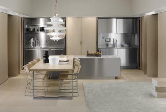 The integrated double-pocket doors of the Spatia kitchen facilitate combining kitchen and living areas while increasing functionality in smaller spaces by hiding cooking, laundry, storage, and wardrobe elements behind a streamlined wall of doors. A table-height island also helps to meld the kitchen and living spaces.