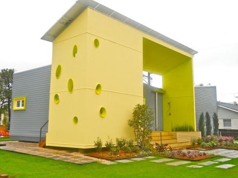 The front elevation of the Sunshower SSIP model serves multiple purposes: On top, it supports a solar panel array; in front, openings give visibility to the structural panels and allow in light and air; and “there’s definitely a playful element” to the design, says architect Judith Kinnard, who adds that the yellow might suggest the sun’s rays.
