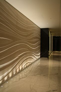 The long sweeping wave pattern in the carved stone artwork at the entrance is uplight to highlight the stone texture.