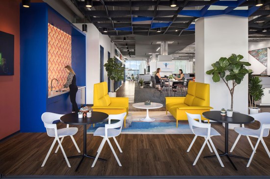 The common area features an orange tiled kitchen backsplash, grid-patterned ceiling designs, and dark hardwood floors that complete the unique design of this environment