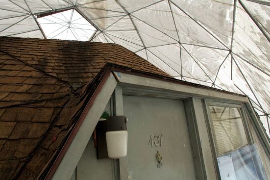 A fabric dome covers the original structure, itself covered in many layers of asphalt roofing shingles.