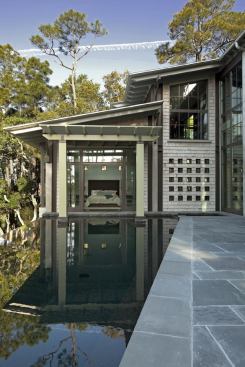 The master bedroom pavilion, surrounded by live oak, pine, and cedar trees, looks out over the black-painted swimming pool.