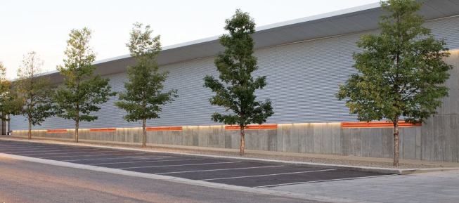 A band of light from 3500K T5HO fluorescent lamps in 4-foot lengths, located along the concrete foundation, provides pedestrian lighting for the sidewalks that run along the north and south faces of the building and the parking lot.