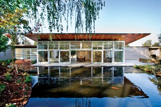 A butterfly roof opens up the main house to the landscape and pond.