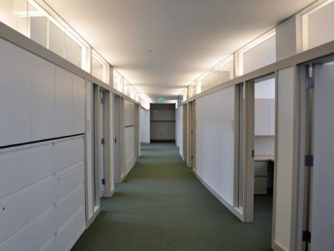 Clerestories bring daylight into the corridors so that they only use electric light when necessary. T5 strips, which indirectly light both the offices and corridors, are integrated continuously into the base of the curving clerestories to keep the surface area of the ceiling uncluttered.