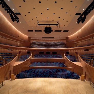 A view from the stage of Helzberg Hall looking out at the seating area. The hall is outfitted with both architectural lighting and theatrical lighting systems. The perimeter of the space is accented by PAR38 IR wallwashers that line the ceiling cove.