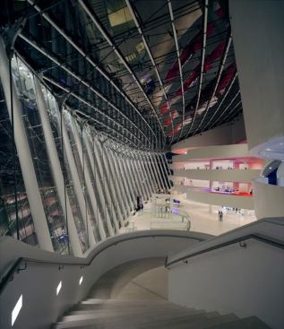 A view of Brandmeyer Great Hall from the staircase leading off of the perimeter balcony corridors of Helzberg Concert Hall. The perimeter balcony corridors of the Muriel Kauffman Theatre are seen in the distance. Lighting is made discreet to blend into the architecture.