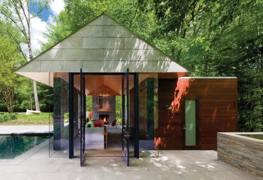 A low-pitched, terne coated stainless steel roof floats above a dry-stacked slate wall and mahogany volume.