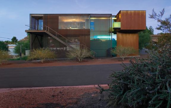 A lime-green, laminated glass balcony supplies a bold contrast to the project's rusted steel building.