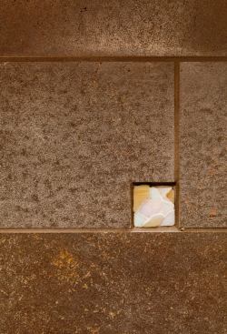 Recessed mosaic tile insets on the backsplash were crafted with bits of snipped glass. They interrupt the strict tile grid while defining it and lending a hand-hewn feel.