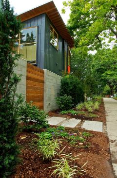 A gabion basket rock wall provides privacy in the busy urban neighborhood. It is softened by a variety of ornamental grasses.