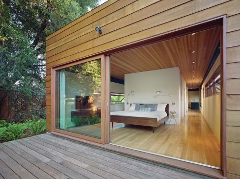 The master bedroom, in the eastern end of the house, features a white oak floor and Douglas Fir ceiling, and sliding panels that open onto a private deck.