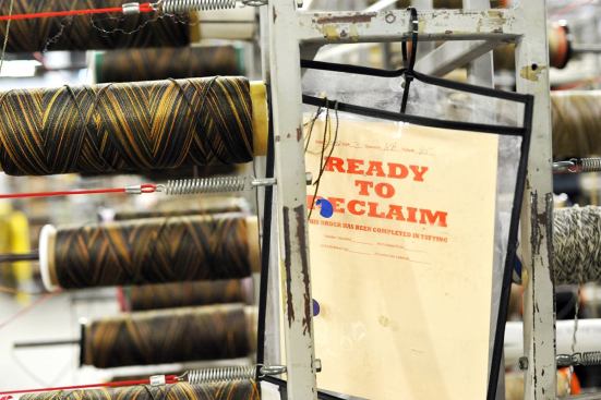 Cones with excess yarn from the tufting process are marked for reclamation.