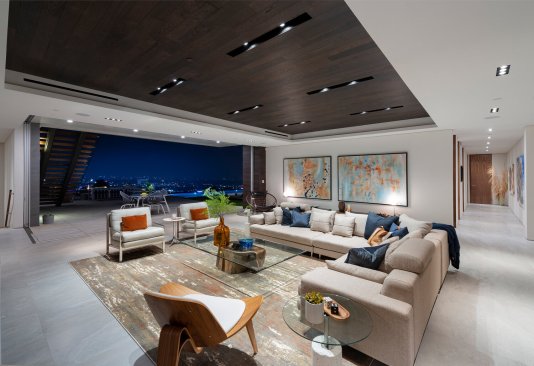 Modern luxury home open plan dining room, bar and kitchen with sliding glass walls open to the views.