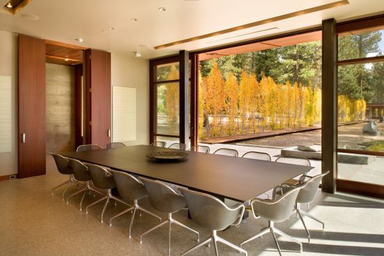 Polished brown concrete floors, mahogany built-ins, and exposed-aggregate concrete decks reinforce the colors and textures found on the site.