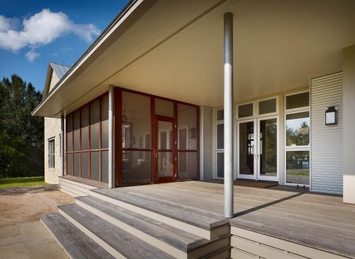 Deep, sheltered porches bracket the house at its entrance (shown) and rear elevations. Closer inspection reveals modernist detailing.