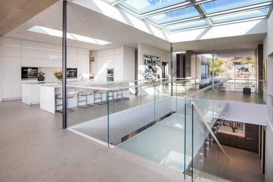 Open plan luxury Beverly Hills home with glass bridge walkway between the kitchen and living room.