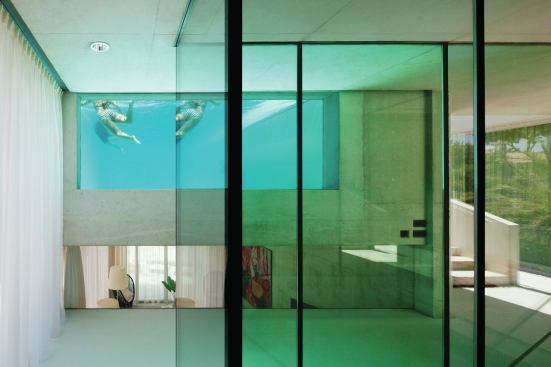 Glazed walls on the first floor offer views into the living area below and the pool above.