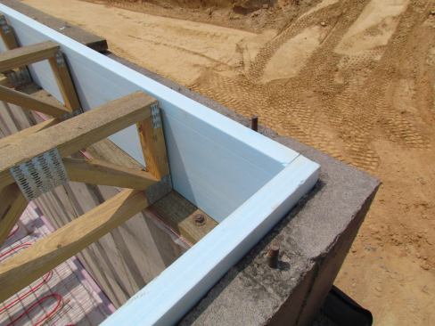 Extruded polystyrene insulation provides a thermal break between floor trusses and poured concrete basement walls.