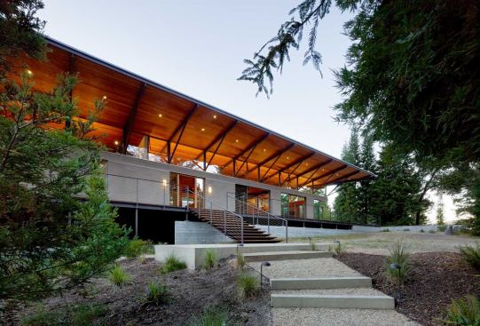 The uphill approach affords a view into the structural workings of the house’s broad, overhanging roof.