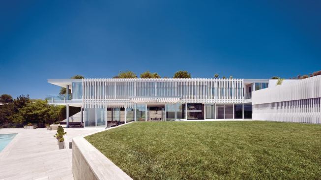 Vertical sunscreen fins cover the L-shaped, one-room-wide house.
