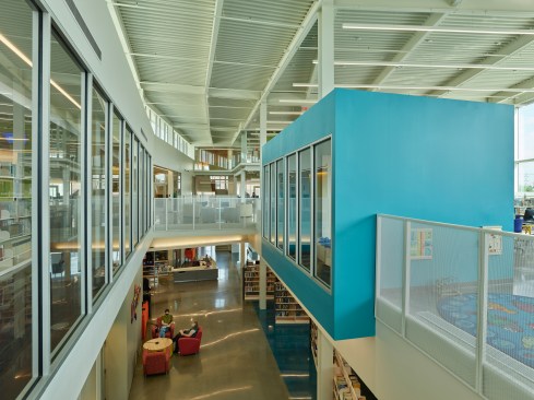 The plan parti creates a pedestrian intersection at the circulation desk as an internal street lit from above.  A continuous clerestory allows the cloud-like roof to cleanly float free, flooding both floors with light.