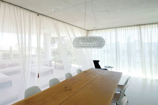 The first-floor dining area features sliding glass doors that open the space entirely to a wide terrace beyond.