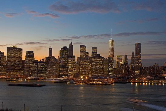 Evening view of the Manhattan skyline from Brooklyn, showing the illuminated spire at 1 World Trade Center. It has now been decided that the spire will be lit with LEDs instead of incandescent fixtures.