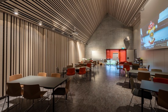 The building is clad with fibre cement sheets of varying shades of red