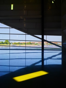 Polished concrete floors bring the river inside the space.  A gold glass “note” moves as the sun changes position.  As stationary, reflected, and direct light, the gold glass “notes” add an ever-changing kinetic energy to the space.