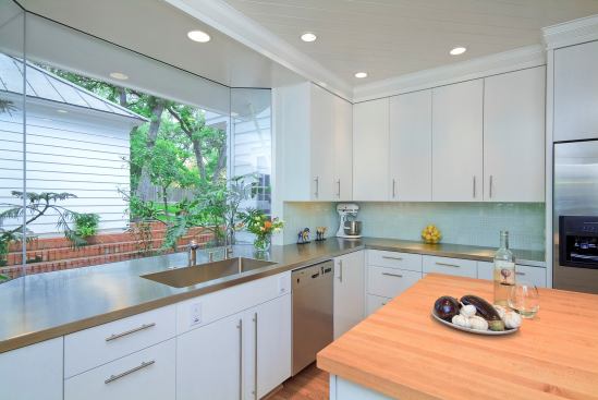 Sleek hardware and stainless steel countertops are softened and warmed by butcher block in this all-white kitchen. Location: Austin, Tex. Architect: Stewart Davis. Builder: CG&S Design-Build.