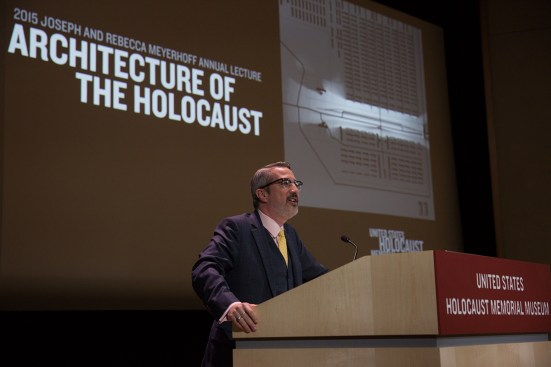 Jaskot delivering the Joseph and Rebecca Meyerhoff Annual Lecture at the United States Holocaust Memorial Museum in Washington, D.C. The image behind him is a viewshed visualization by Chester Harvey that shows what a guard could see from the ramp of Auschwitz-Birkenau.