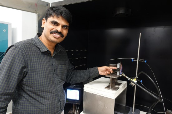 NTU Singapore's assistant professor Aravind Dasari putting his finger on a piece of plastic that is cool enough to touch, which was placed behind a steel plate coated with FiroShield and exposed to a flame over 900 degrees Celsius (1,652 degrees Fahrenheit)
