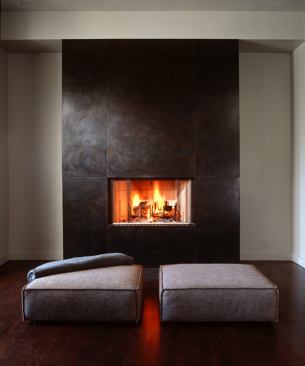 The living room’s steel-clad fireplace balances the lightness of the open stairway.