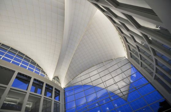 From inside the main atrium looking up at the  sail-like roof structure. T5HO forward-throw cove luminaires are located in the  tops of the perimeter walls to light the space. Digital addressable ballasts  allow light output to be tuned along the roof perimeter to accent the curvature  of the forms.