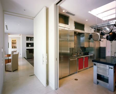 Full-height pivoting doors flank a large wine fridge and lead to a professional-grade kitchen.