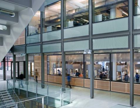 In the atrium lobby, round, exterior-style  luminaires are paired on custom brackets that also serve as the ballast  enclosure.