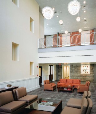 A new entrance (opposite), denoted by a glass canopy, is positioned along the fa?ade of the addition, providing an entry close to the heart of campus. When students enter, they can see the old Hunt fa?ades preserved within. Original windows have been converted to display cases for the anthropology department (above left). Steel structural members indicate the perimeter of the self-supporting addition and leave the original fa?ades exposed in lounge areas (above right).