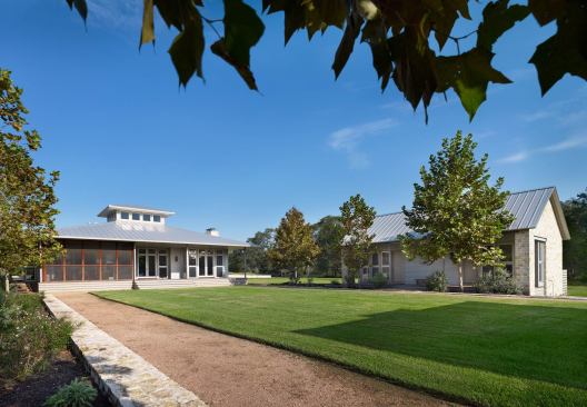 A freestanding guest house flanks the rear yard’s manicured green.