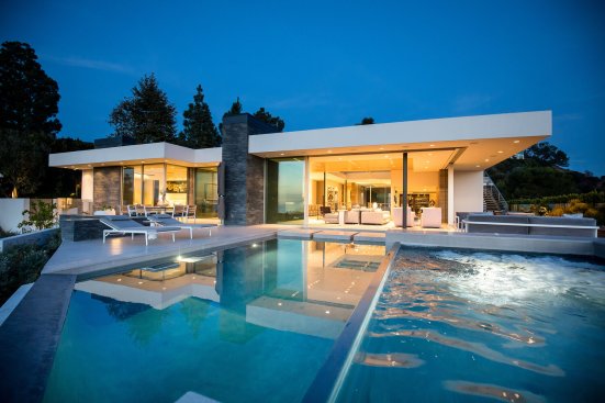 Backyard pool terrace connects directly to the living room through sliding glass walls at modern Beverly Hills home.